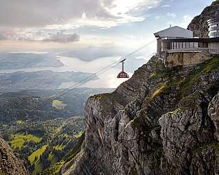 Seilbahn führt über eine beeindruckende Berglandschaft mit Blick auf den See.