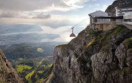 Cable car leads over an impressive mountain landscape with a view of the lake.