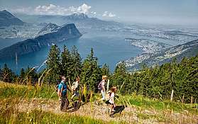 Gruppe von Wanderern mit Blick auf einen See und Berge.