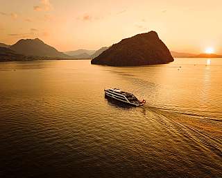 Eine Yacht fährt über einen ruhigen See bei Sonnenuntergang.