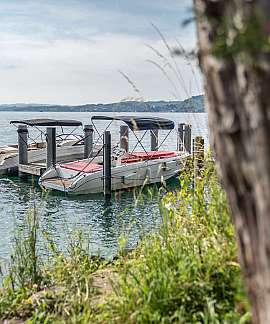 Zwei Boote am Steg in ruhigem Gewässer.