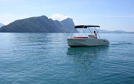 A boat sails on a calm lake with mountains in the background.