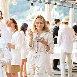 Frau in heller Kleidung genießt Essen auf einer Veranstaltung.