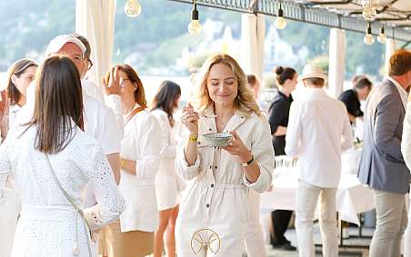 Eine Frau in heller Kleidung lächelt und hält eine Schüssel mit Essen.