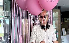 Ein DJ steht mit rosa Ballons und Mischpult.