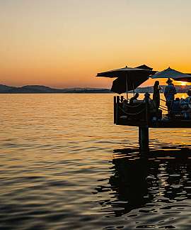 People on a jetty enjoying the sunset by the lake.