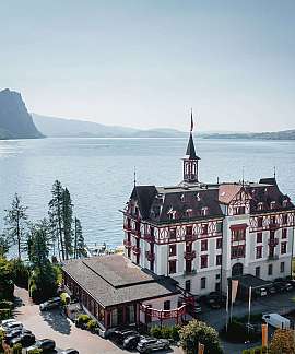 Ein historisches Gebäude mit Blick auf einen ruhigen See und Berge.