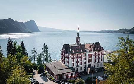 Ein historisches Gebäude mit Blick auf einen ruhigen See und Berge.