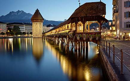 Die beleuchtete Kapellbrücke spiegelt sich im ruhigen Wasser.