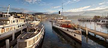Blick auf den Hafen mit mehreren Booten und Bergen im Hintergrund.