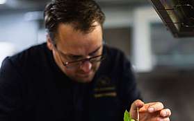 Ein Koch dekoriert ein Gericht in einer modernen Küche.