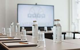 Ein Konferenztisch mit Wasserflaschen und Schreibmaterialien.