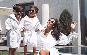 Eine Frau und zwei Kinder in Bademänteln genießen die Sonne.