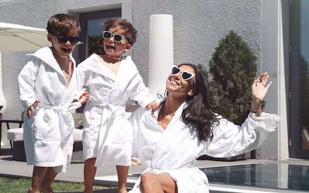 Eine Frau und zwei Kinder in Bademänteln genießen die Sonne.