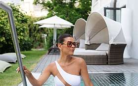 Frau in einem weißen Badeanzug steht im Pool.