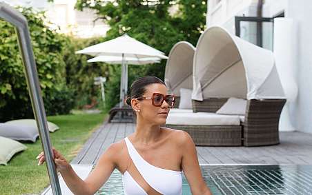 Frau in einem weißen Badeanzug steht im Pool.