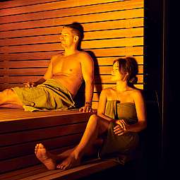 Ein Mann und eine Frau entspannen in einer Holzsauna.