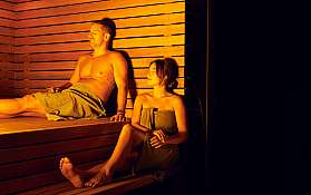 Ein Mann und eine Frau entspannen in einer Holzsauna.