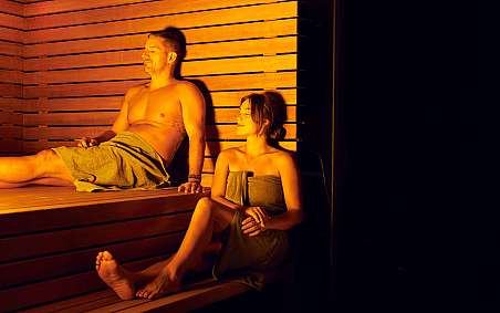 Ein Mann und eine Frau entspannen in einer Holzsauna.