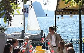 Gruppe von Menschen genießt Getränke und Essen am See.