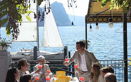 Group of people enjoying drinks and food by the lake.