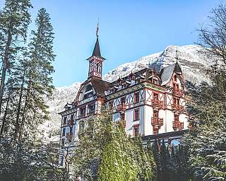 Snow-covered hotel surrounded by trees and mountains.