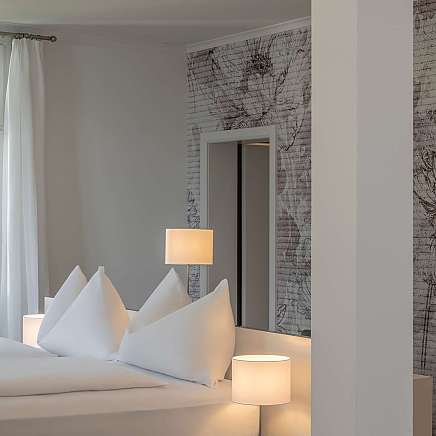 Ein stilvolles Schlafzimmer mit weißen Kissen und sanfter Beleuchtung.