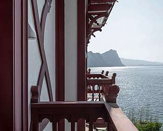 Blick von einem Balkon auf einen See und Berge im Hintergrund.