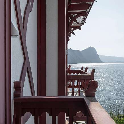 Blick von einem Balkon auf einen See und Berge im Hintergrund.