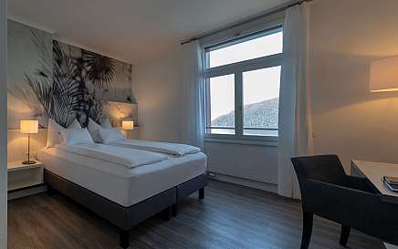 Modernes Hotelzimmer mit zwei Betten und Blick auf die Berge.