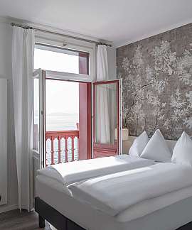 Modernes Schlafzimmer mit zwei Betten und offener Balkontür.