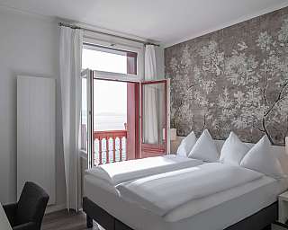 Modernes Schlafzimmer mit offenen Fenstern und floralem Wanddesign.