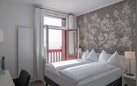 Modernes Schlafzimmer mit zwei Betten und offener Balkontür.