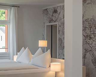 Modernes Schlafzimmer mit weißen Kissen und sanfter Beleuchtung.